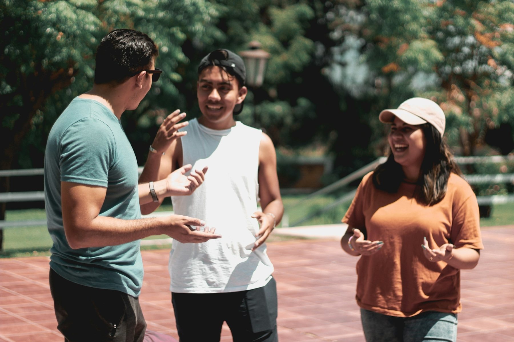 Three people talking and laughing outdoors in the sun
